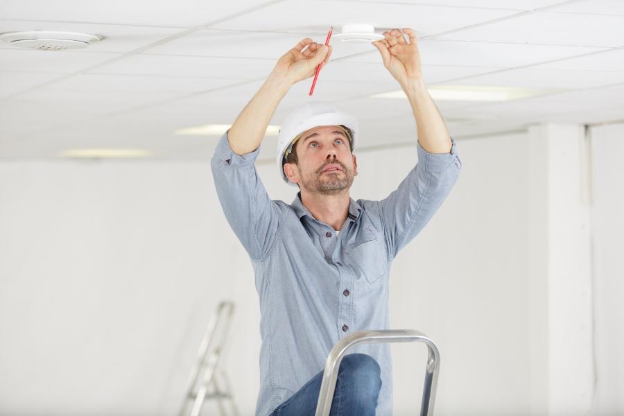 Mann markiert Stelle für neue Lampe mit einem Bleistift