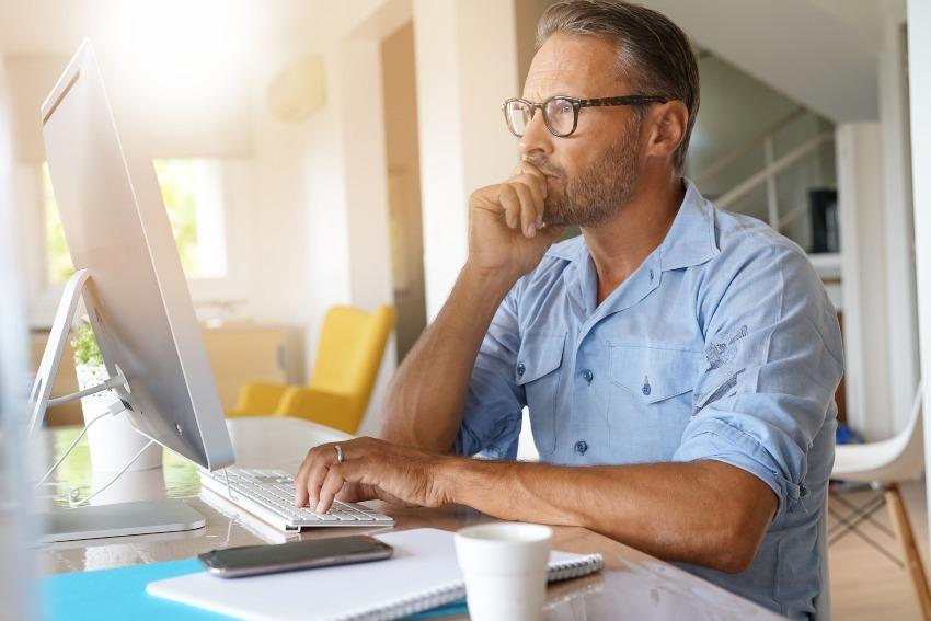 Mann sitzt am Computer mit Brille