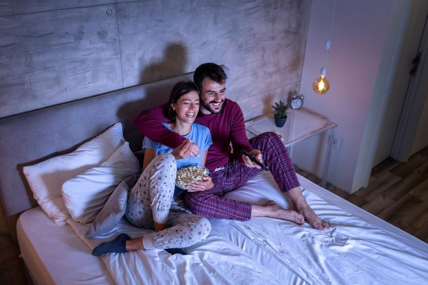 Junges Paar im Bett schaut fern